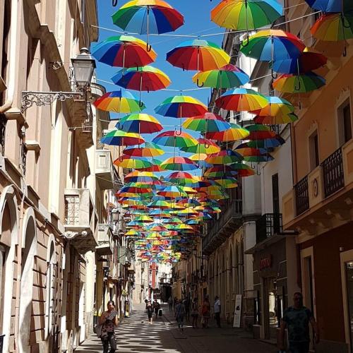 a bunch of colorful umbrellas hanging over a street at B&B Quintino Sella in Iglesias