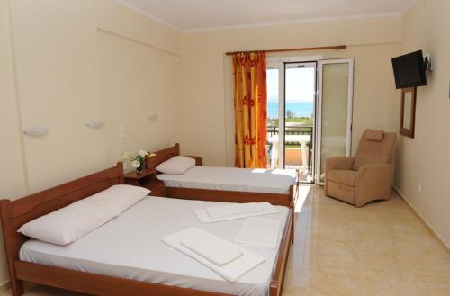 a hotel room with two beds and a chair at Calypso Luxury Studios in Vasiliki