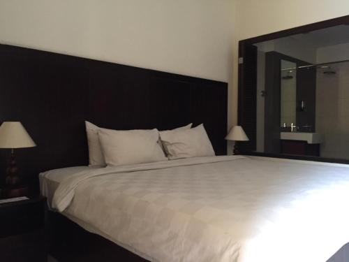 a bedroom with a large white bed with a large mirror at Suris Boutique Hotel in Kuta
