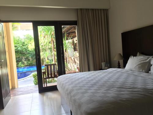 a bedroom with a bed and a sliding glass door at Suris Boutique Hotel in Kuta