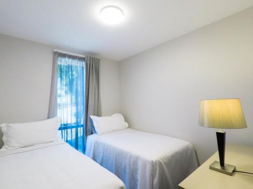 a room with two beds and a lamp and a window at Kerikeri Homestead Motel & Apartments in Kerikeri