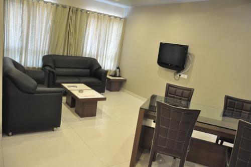 a living room with furniture and a tv on the wall at Lotus Hotel in Solapur