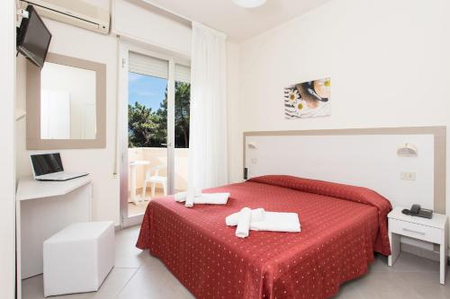 a bedroom with a red bed with a red blanket at Hotel Real in Cervia