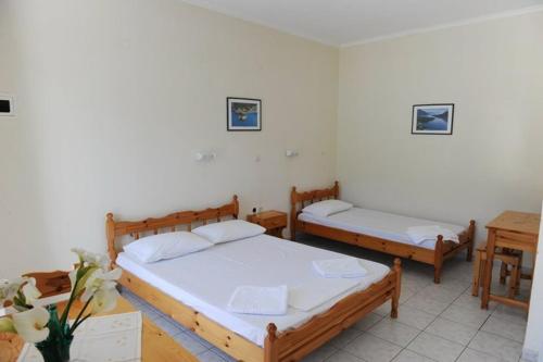 two beds in a room with two tables at Mediterraneo studios in Vasiliki