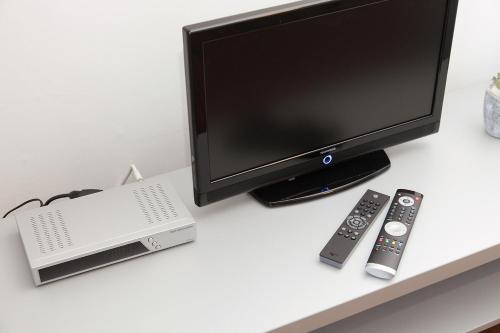 a computer monitor and remote controls on a desk at Pension Arkade Heilbronn in Heilbronn