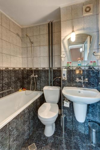 a bathroom with a toilet and a sink and a tub at Family Hotel Prestige in Burgas
