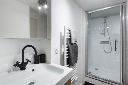 une salle de bain blanche avec un lavabo et une douche dans l'établissement Les Lices by Cocoonr, à Rennes