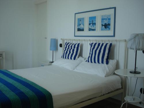 a white bed with blue and white pillows on it at Globetrotter in Formia