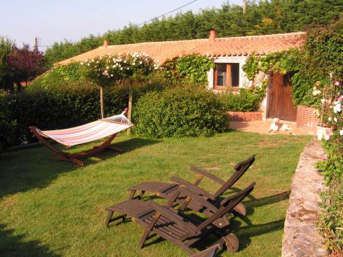 a hammock and a chair in the yard of a house at Chambres d'Hôtes La Forterie in Vairé