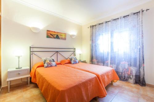 a bedroom with a bed with an orange bedspread at Sa Tanca -Mancorina- in Mancor del Valle