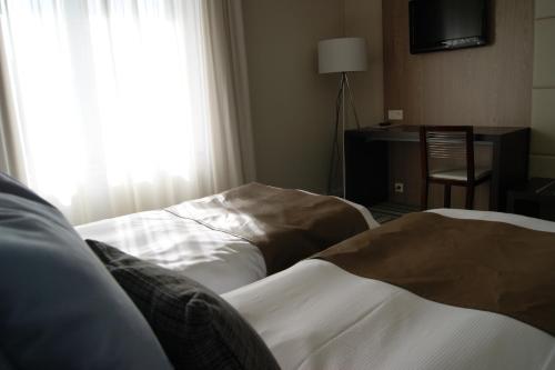 a hotel room with two beds and a window at Hotel Malpertuus in Riemst