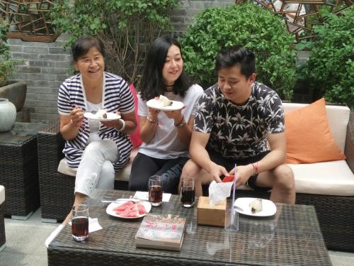 a group of three people sitting on a couch eating food at Water Hotel, Pingyao in Pingyao