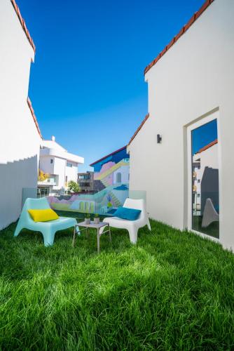 two chairs and a table in the grass next to a building at Nayino Resort Hotel in Mamaia Nord