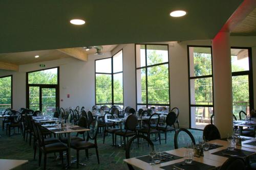 een eetkamer met tafels, stoelen en ramen bij Le Pré du Lac in Saint-Jorioz