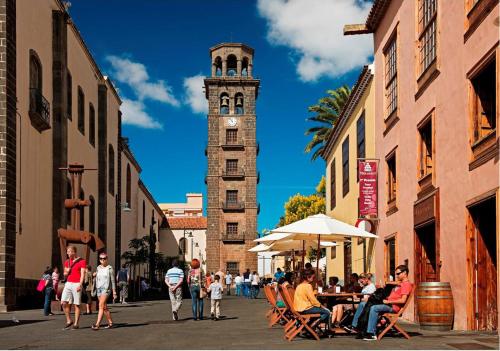 a clock tower with a crowd of people walking down a street at Atico La Laguna con terraza y vistas in Las Lagunas