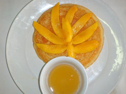 a plate with a sandwich with mango slices on it at Deep Forest Garden Hotel in Puerto Princesa City