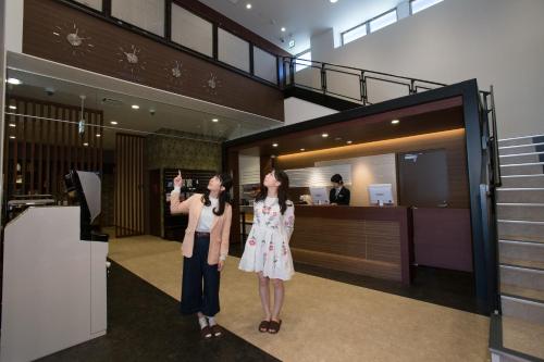 
women standing in front of a building at Mt.Fuji Cabin & Lounge Highland Station Inn (Capsule Hotel) in Fujikawaguchiko

