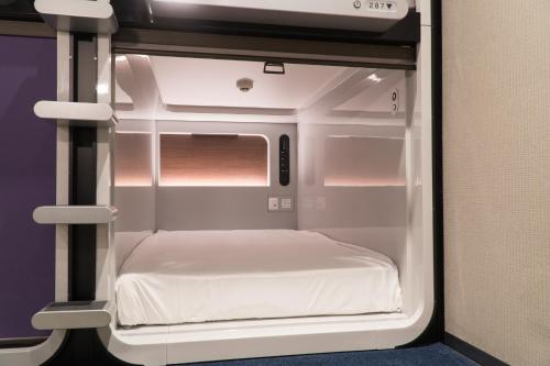 a small white room with a bed in it at Mt.Fuji Cabin & Lounge Highland Station Inn (Capsule Hotel) in Fujikawaguchiko