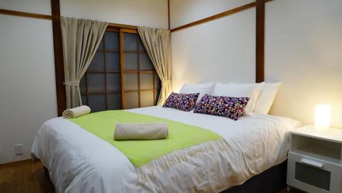 a bedroom with a large bed with a green blanket at Harmony House Hakuba in Hakuba