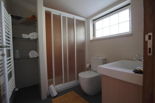 La salle de bains est pourvue de toilettes, d'un lavabo et d'une fenêtre. dans l'établissement A Casa da Lena, à Foz do Cobrão