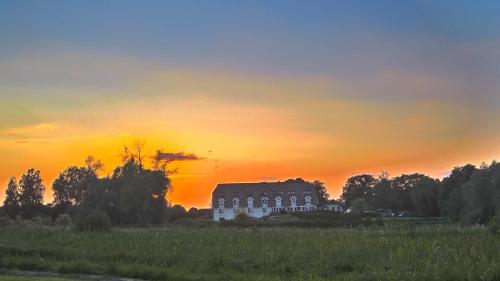a house in a field with a sunset in the background at Alago Hotel am See in Cambs