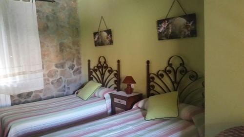 two twin beds in a room with a window at Casa Rural El Nido del Cuco in Valdeobispo