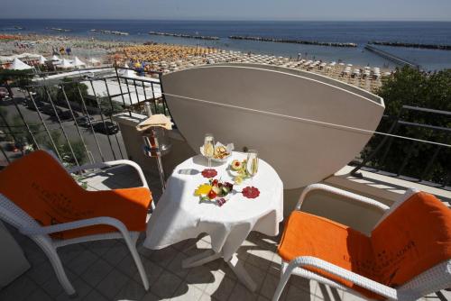 een tafel en stoelen op een balkon met uitzicht op het strand bij El Cid Campeador in Rimini