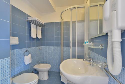 bagno piastrellato blu con lavandino e servizi igienici di Hotel Mareluna a Castellabate