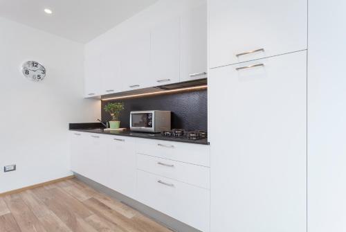 a kitchen with white cabinets and a microwave at VillaGiardino - Lake in Molveno