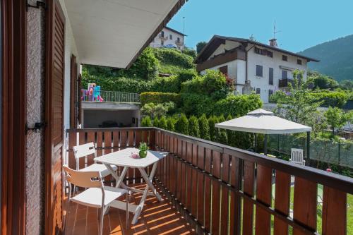 a balcony with a table and chairs and an umbrella at VillaGiardino - Lake in Molveno