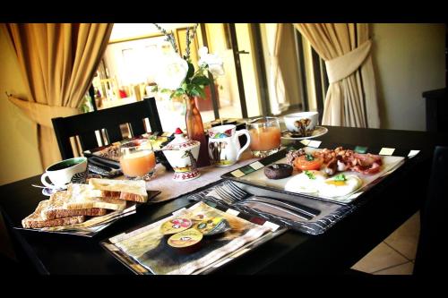 a table with breakfast foods and drinks on it at Blue Hills Lodge in Midrand