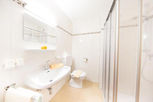 a white bathroom with a toilet and a sink at Pension Charly in Sölden