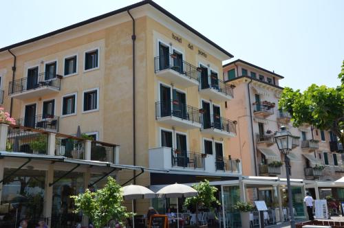 a building with tables and umbrellas in front of it at Hotel Del Porto in Torri del Benaco