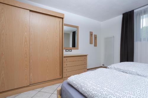 a bedroom with a bed and a dresser with a mirror at VillaGiardino - Lake in Molveno