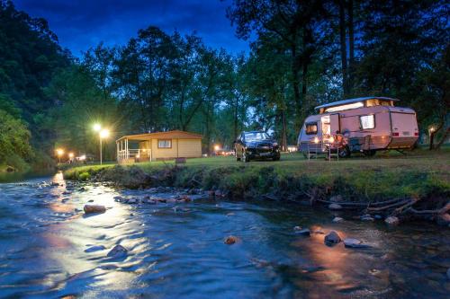 a camper and a truck parked next to a stream at Merry Pebbles Resort in Sabie