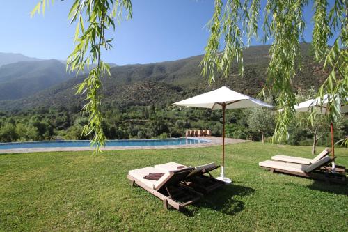 two lounge chairs and an umbrella next to a pool at Kasbah Africa - High Atlas Dark Sky & Nature Lodge in Ouirgane