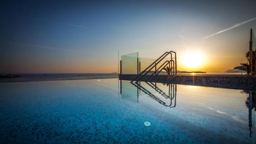 a swimming pool with a stairway in front of the sunset at Royal Blue Hotel in Dubrovnik
