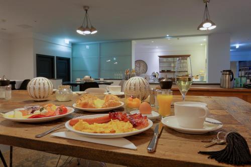 a wooden table topped with plates of food and drinks at FourSide Plaza Hotel Trier, Trademark Collection by Wyndham in Trier