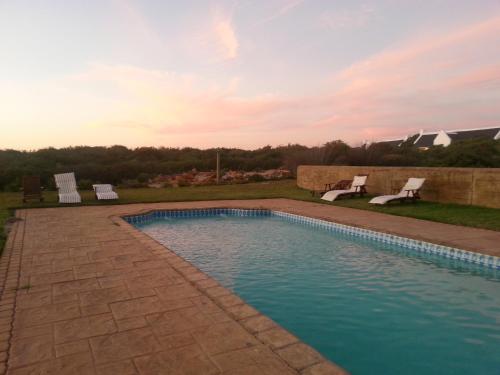 a swimming pool with two chairs in a yard at Draaihoek Lodge & Restaurant in Elands Bay
