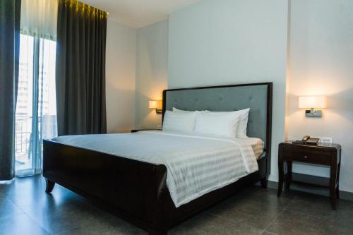 a bedroom with a large bed with white sheets and a window at The Sala Pattaya - SHA Certified in Jomtien Beach