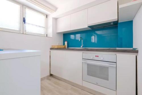 a kitchen with white cabinets and blue walls at Apartment Fontana in Belgrade