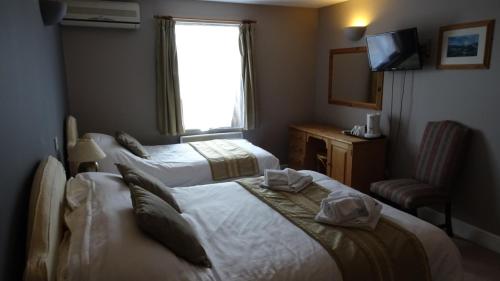 a hotel room with three beds and a television at The Furze Bush Inn in Newbury