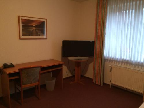 a room with a desk with a computer monitor and a table at Zur Krone in Seelze