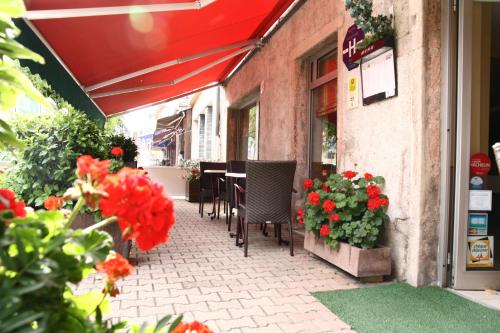 un patio con sillas y flores fuera de un restaurante en Logis Hotel L'ange Couronne, en Belleville-sur-Saône