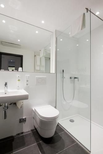 a bathroom with a toilet and a shower and a sink at FourSide Plaza Hotel Trier, Trademark Collection by Wyndham in Trier
