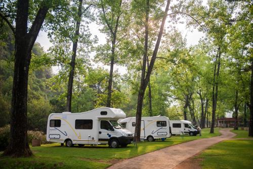 a group of three rvs parked in a park at Merry Pebbles Resort in Sabie