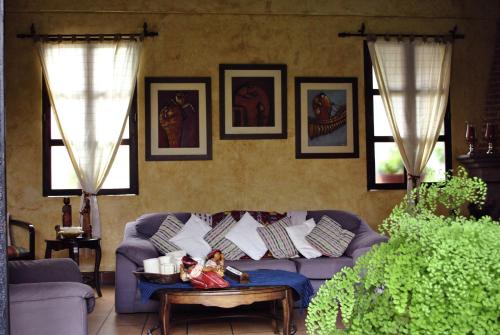 a living room with a purple couch and paintings on the wall at Hotel Las Marias in Antigua Guatemala