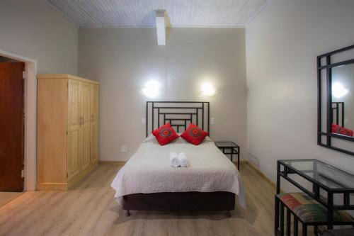 a bedroom with a bed with two red pillows at Merry Pebbles Resort in Sabie