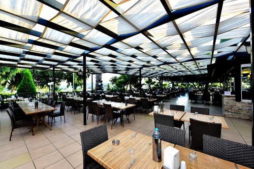 a restaurant with wooden tables and chairs and a roof at Parkim Ayaz Hotel in Gümbet