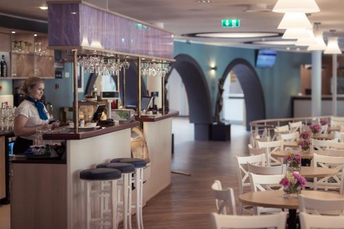 a woman standing at a bar in a restaurant at Hestia Hotel Strand in Pärnu